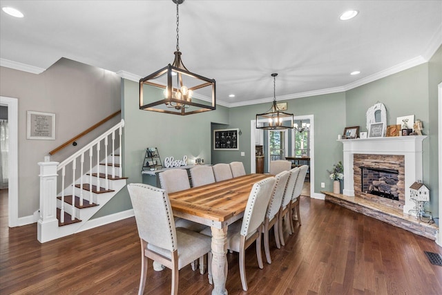 dining area featuring a fireplace, crown molding, a chandelier, and dark hardwood / wood-style floors