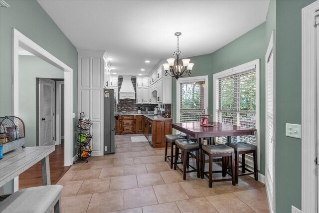 dining space featuring light tile patterned floors, an inviting chandelier, and sink