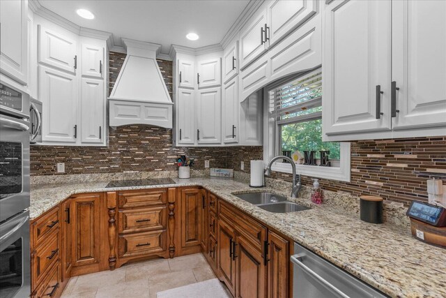 kitchen with custom range hood, sink, white cabinetry, and tasteful backsplash