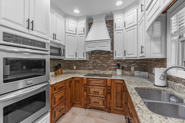 kitchen with premium range hood, appliances with stainless steel finishes, sink, and white cabinets