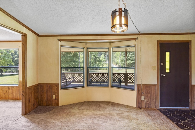interior space with carpet flooring, ornamental molding, and a wainscoted wall