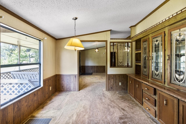 unfurnished dining area with wood walls, crown molding, and a wainscoted wall