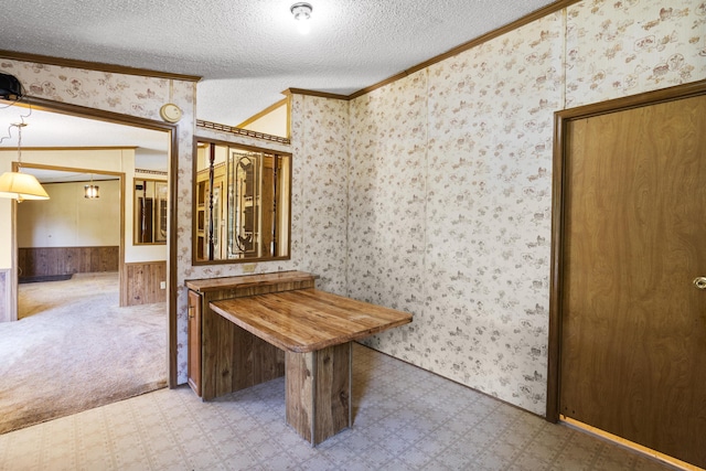hallway with crown molding, tile patterned floors, a wainscoted wall, and a textured ceiling