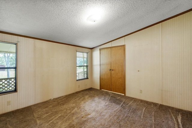 unfurnished bedroom featuring carpet, multiple windows, ornamental molding, and vaulted ceiling