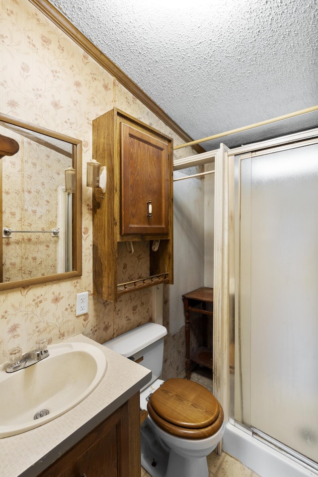 bathroom featuring toilet, a textured ceiling, crown molding, wallpapered walls, and a stall shower
