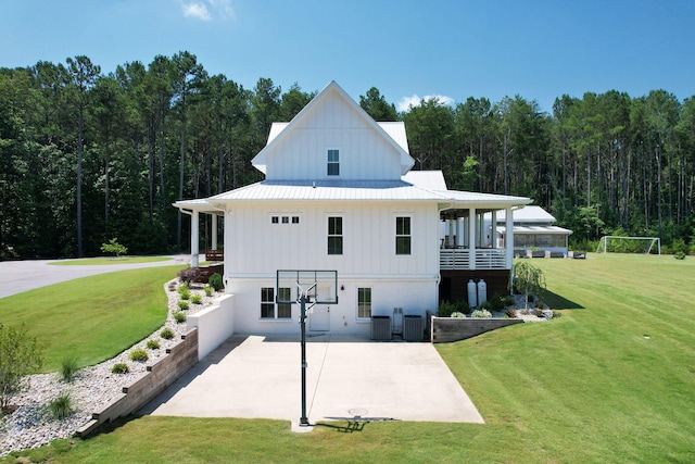 rear view of house featuring covered porch, central AC unit, and a lawn