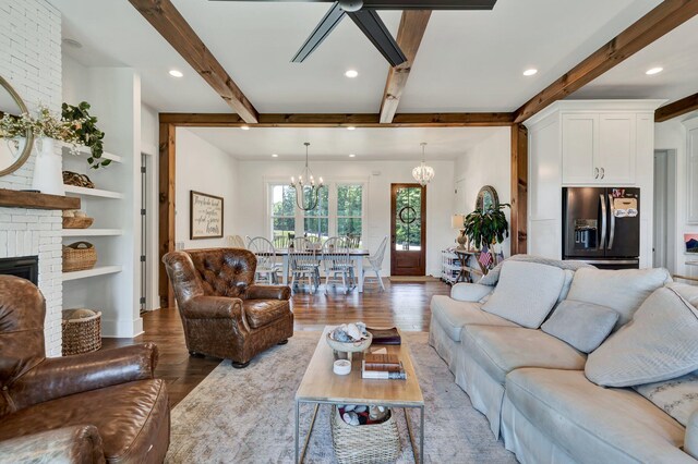 living room featuring hardwood / wood-style flooring, a brick fireplace, beam ceiling, and a notable chandelier