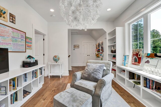 sitting room featuring hardwood / wood-style flooring, an inviting chandelier, and vaulted ceiling