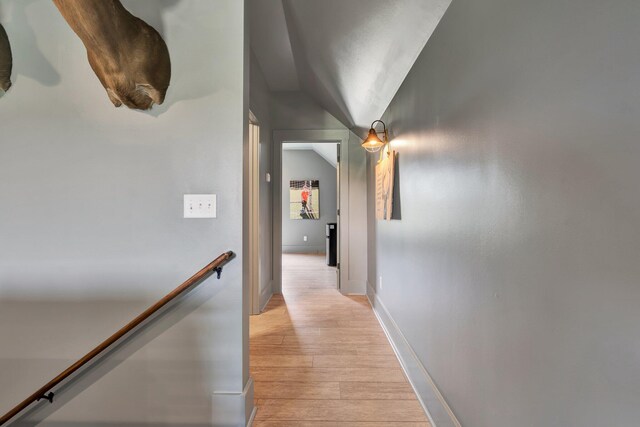 corridor with lofted ceiling and light hardwood / wood-style floors