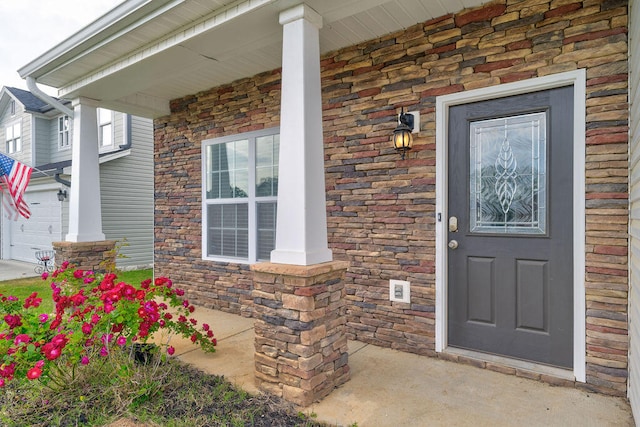 view of exterior entry featuring a garage and a porch