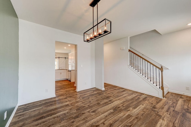 unfurnished living room with a barn door and dark hardwood / wood-style flooring