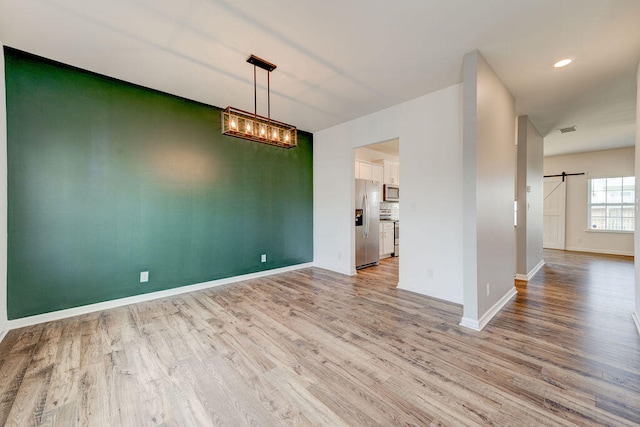 unfurnished dining area with light hardwood / wood-style flooring and a barn door