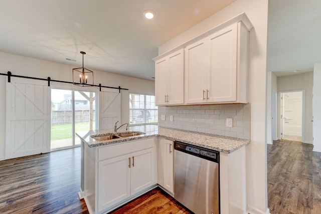 kitchen with a barn door, dark hardwood / wood-style floors, kitchen peninsula, and stainless steel dishwasher