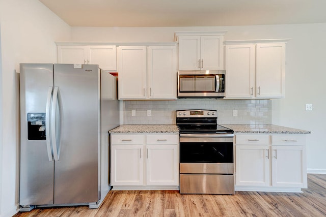 kitchen featuring white cabinetry, light stone counters, stainless steel appliances, and light hardwood / wood-style floors