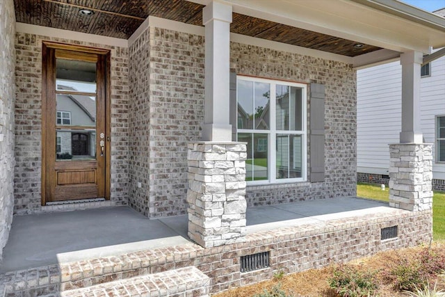 doorway to property with crawl space, covered porch, and brick siding