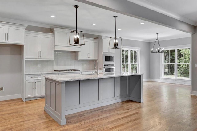 kitchen with a center island with sink, pendant lighting, a wealth of natural light, and light wood-type flooring