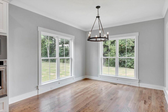 unfurnished dining area with light hardwood / wood-style flooring, ornamental molding, and a chandelier