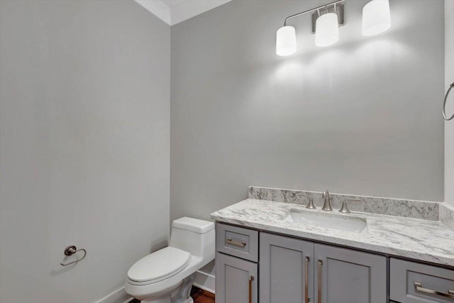 half bath featuring toilet, vanity, and baseboards