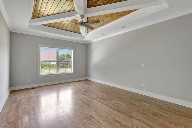 unfurnished room with a ceiling fan, wood finished floors, baseboards, a tray ceiling, and ornamental molding