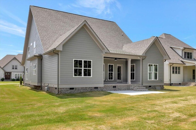 rear view of house featuring crawl space, a lawn, roof with shingles, and a patio area