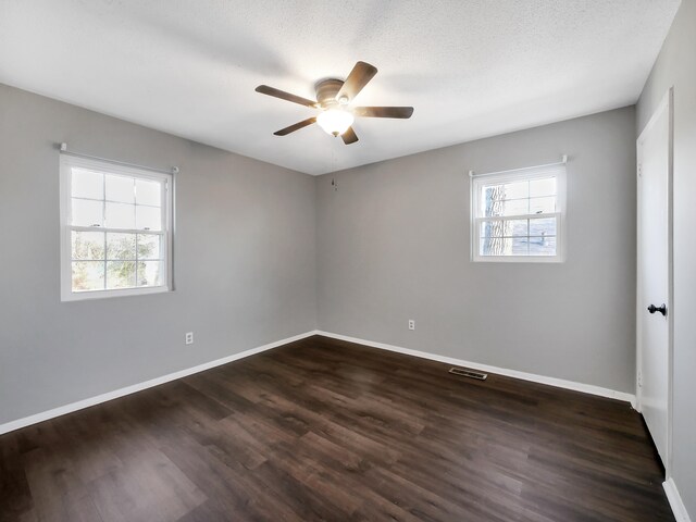 unfurnished room with ceiling fan, plenty of natural light, dark hardwood / wood-style flooring, and a textured ceiling