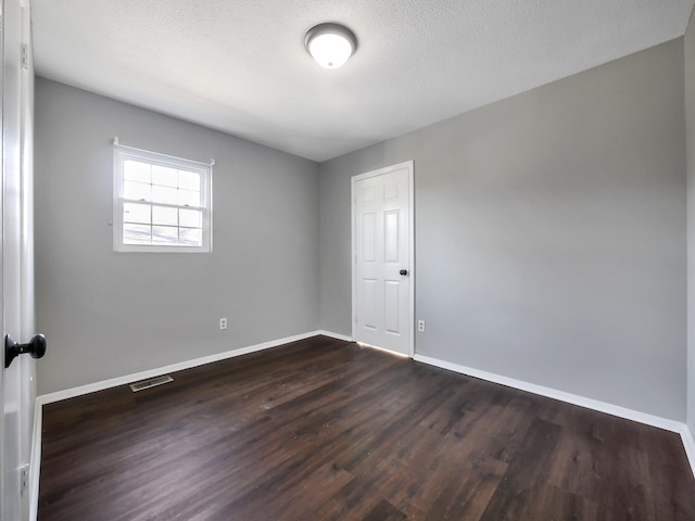 spare room with dark hardwood / wood-style flooring and a textured ceiling