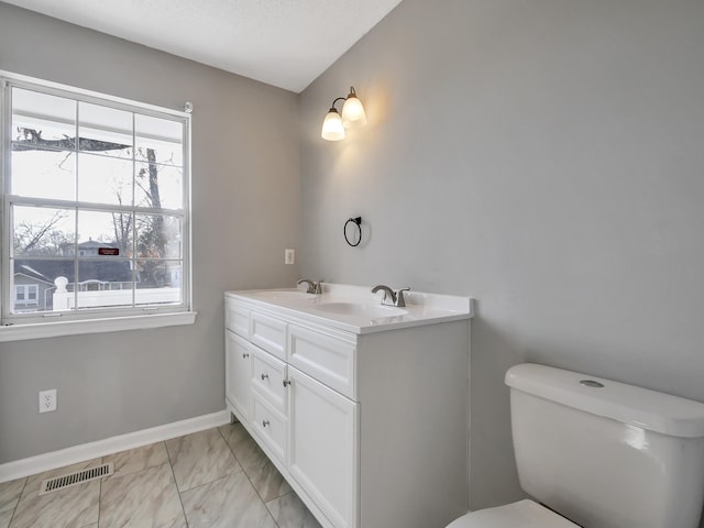 bathroom with vanity, toilet, and a wealth of natural light