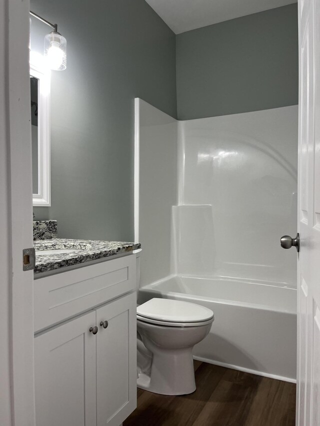 full bathroom featuring vanity, hardwood / wood-style floors, shower / washtub combination, and toilet