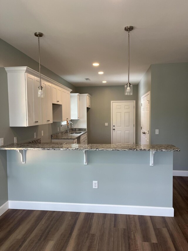 kitchen featuring dark wood-type flooring, kitchen peninsula, and pendant lighting