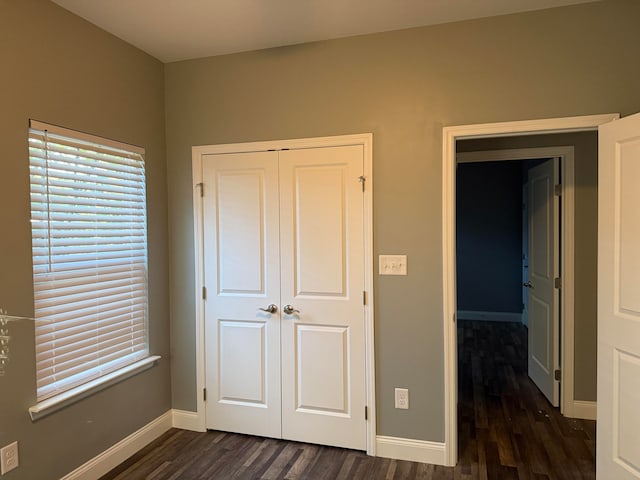 unfurnished bedroom featuring dark wood-type flooring and a closet