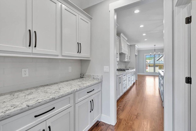 bar featuring wood finished floors, baseboards, an inviting chandelier, recessed lighting, and backsplash