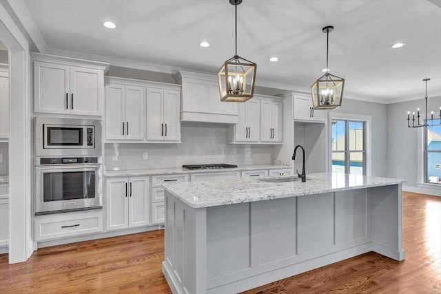 kitchen featuring appliances with stainless steel finishes, pendant lighting, light hardwood / wood-style floors, and sink