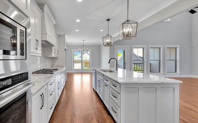 kitchen featuring appliances with stainless steel finishes, sink, a kitchen island with sink, and light hardwood / wood-style flooring