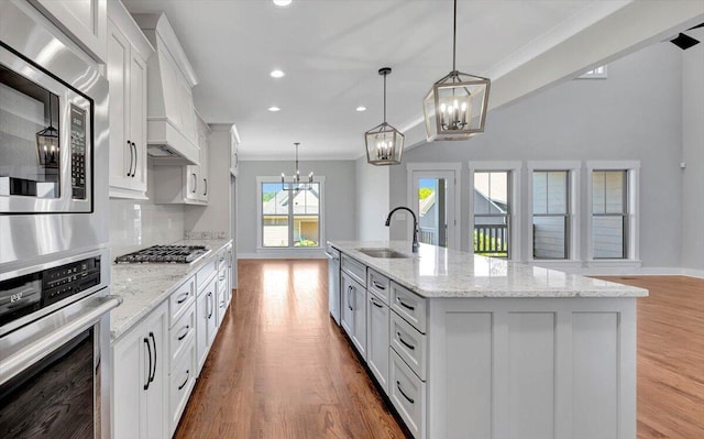 kitchen with a sink, tasteful backsplash, wood finished floors, white cabinetry, and appliances with stainless steel finishes