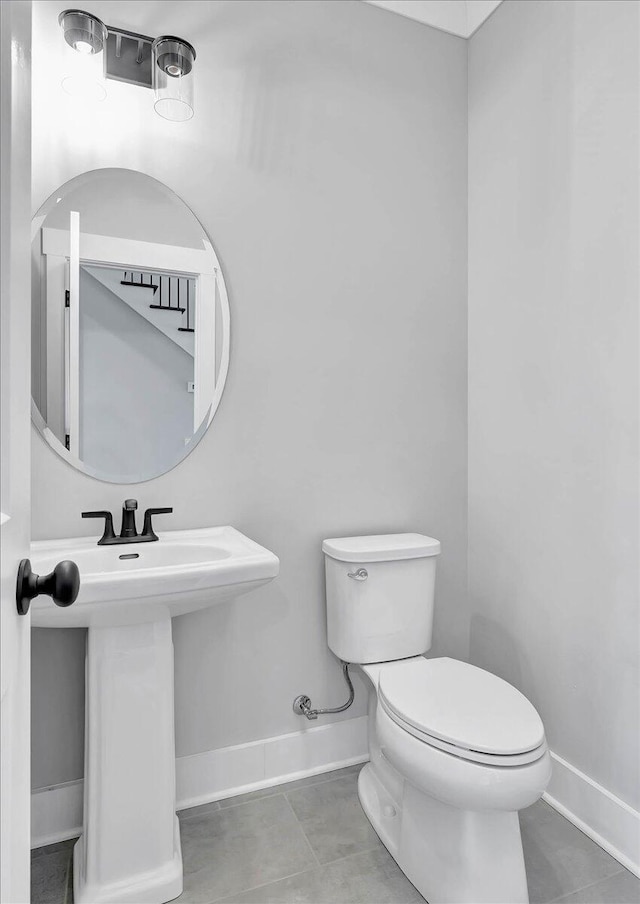 bathroom with tile patterned flooring, toilet, baseboards, and a sink