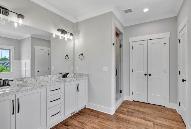 bathroom featuring hardwood / wood-style floors, an enclosed shower, ornamental molding, and vanity