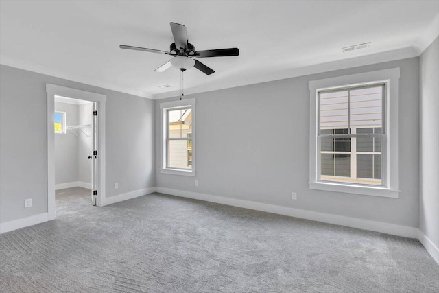 empty room with visible vents, baseboards, carpet floors, ceiling fan, and ornamental molding