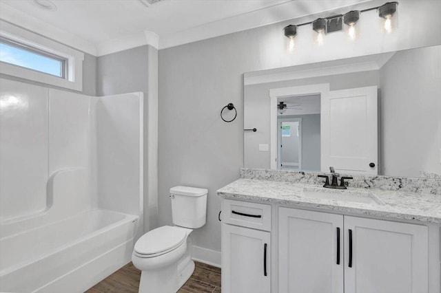 bathroom featuring toilet, wood finished floors, shower / bathing tub combination, baseboards, and vanity