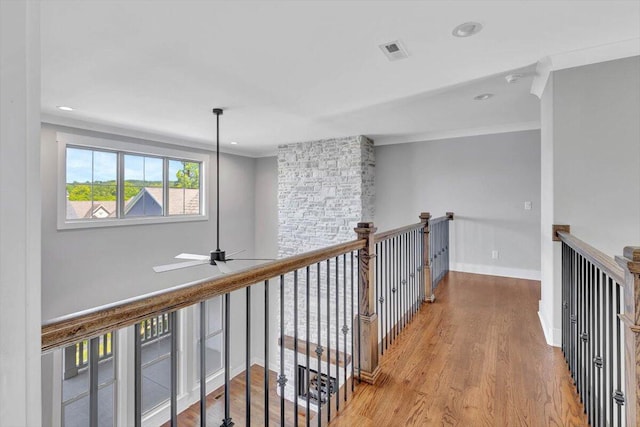 hall featuring visible vents, baseboards, wood finished floors, and ornamental molding