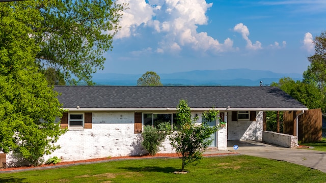 ranch-style home featuring a mountain view and a front lawn