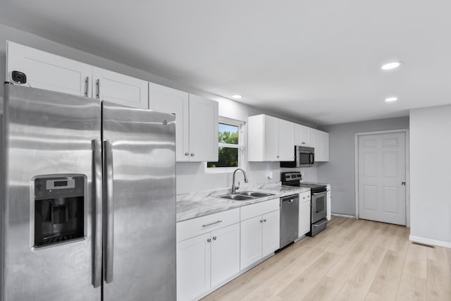 kitchen with stainless steel appliances, white cabinetry, light hardwood / wood-style floors, and sink