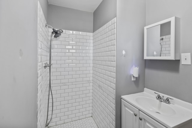 bathroom with a tile shower and vanity