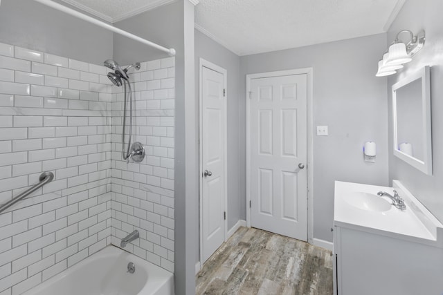 bathroom with wood-type flooring, a textured ceiling, tiled shower / bath, and vanity