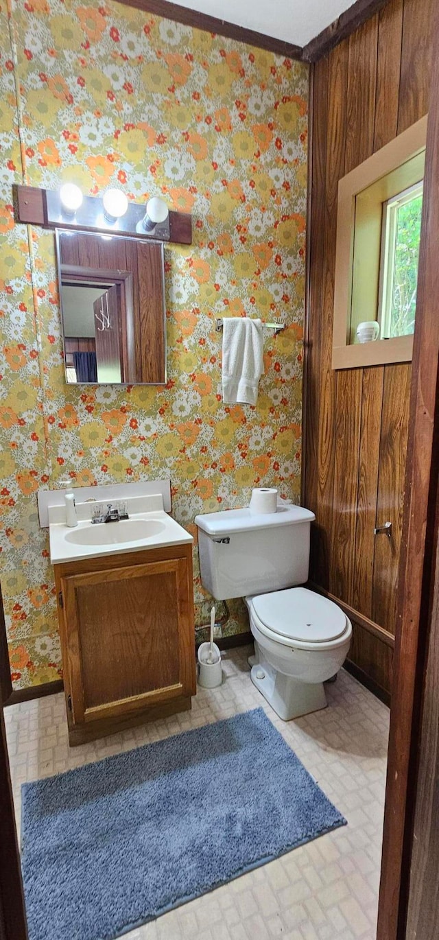 bathroom featuring ornamental molding, vanity, toilet, and wood walls