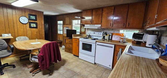 kitchen featuring wood walls, sink, and white appliances