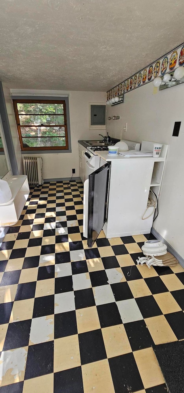 laundry area with a textured ceiling, cabinets, radiator, and washing machine and clothes dryer