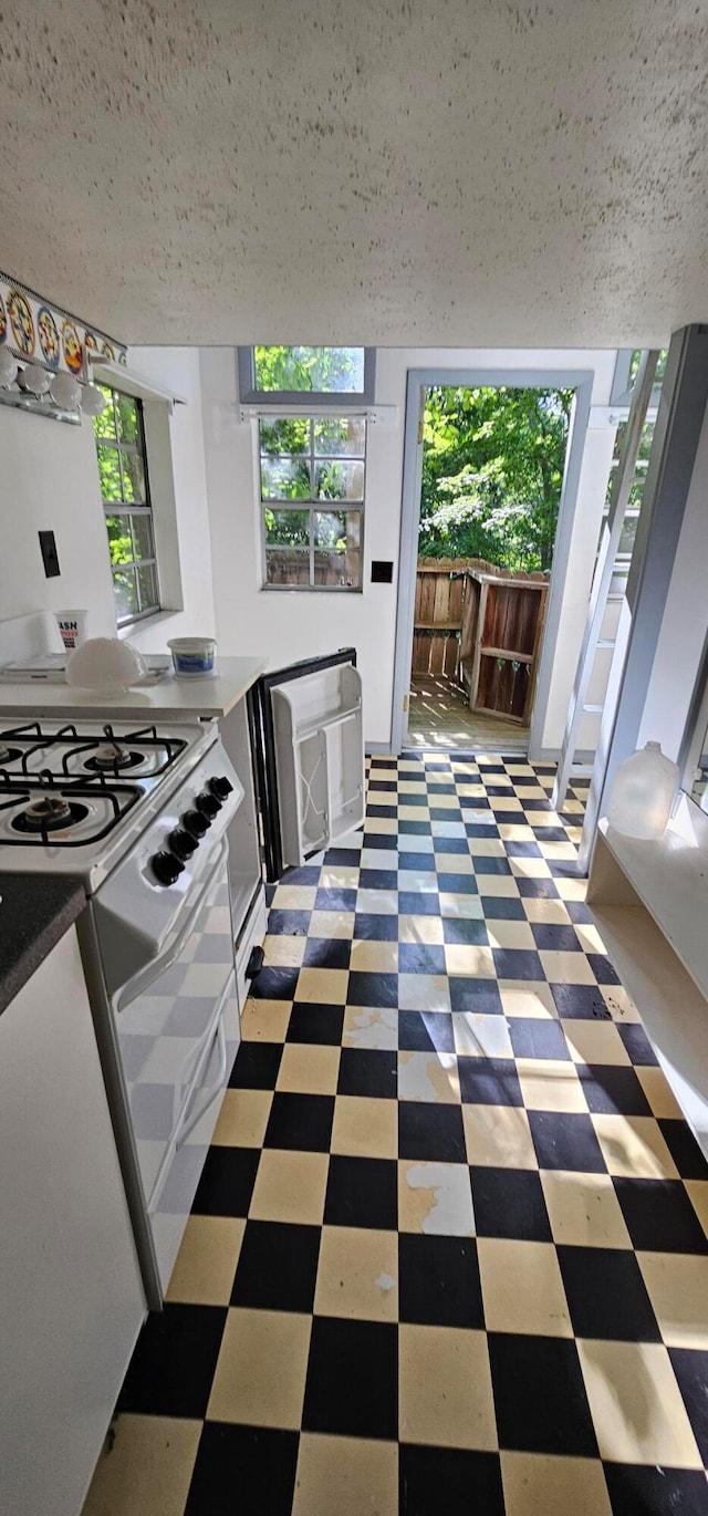 kitchen with white gas stove and a textured ceiling