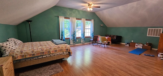 bedroom with vaulted ceiling, a textured ceiling, wood-type flooring, and ceiling fan