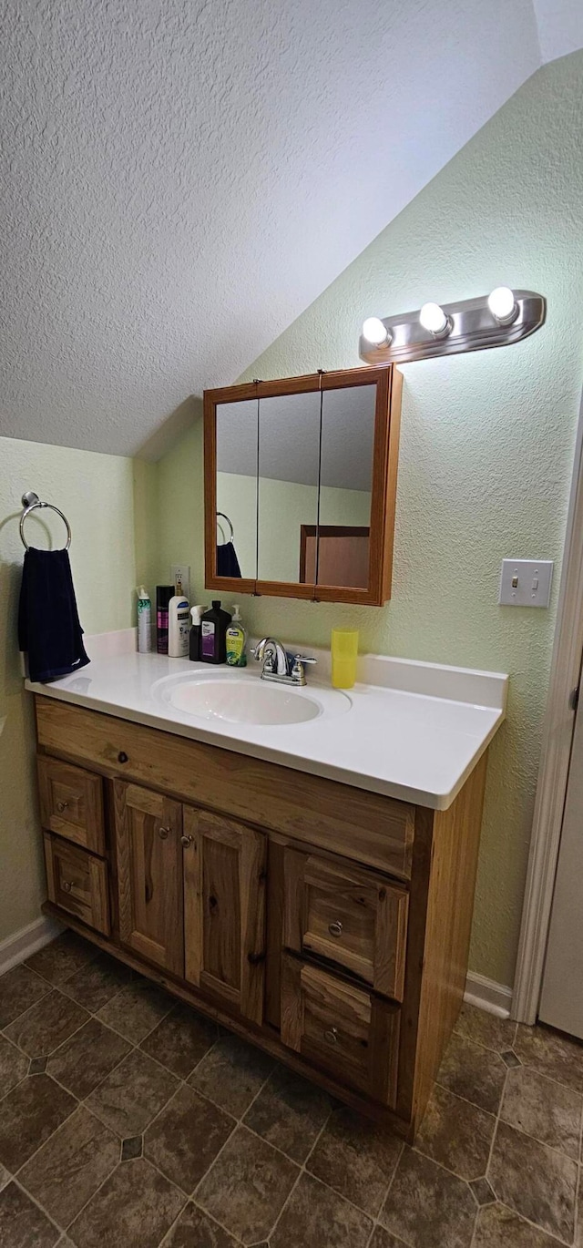 bathroom with a textured ceiling, vanity, and vaulted ceiling