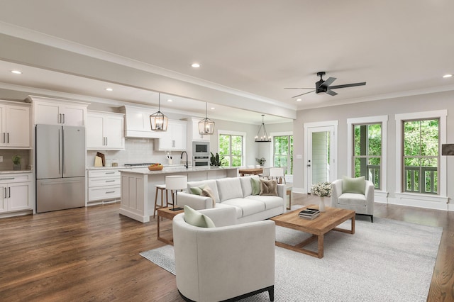 living room featuring ceiling fan with notable chandelier, dark hardwood / wood-style floors, and ornamental molding